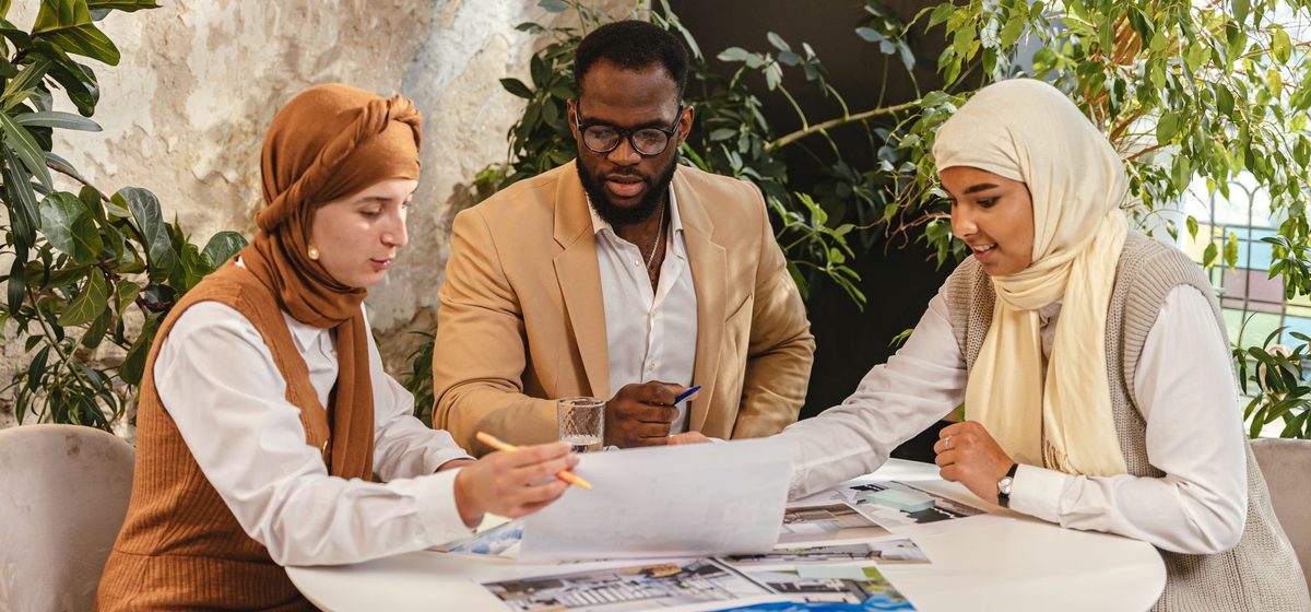 Three colleagues working through a set of documents together at a table.